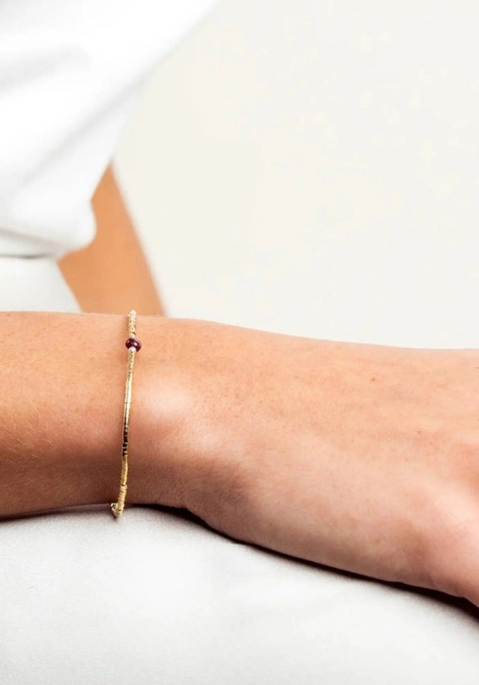 Bracelet fin en or laminé et grenat porté - Têtes Blondes